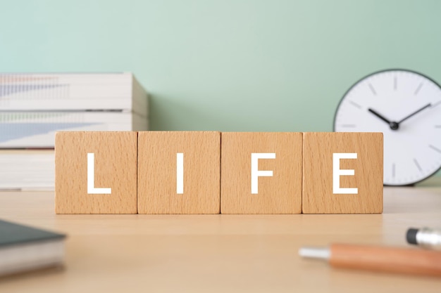 Photo wooden blocks with life text of concept, pens, notebooks, and books.