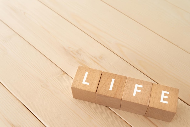 Photo wooden blocks with life text of concept on the wooden floor.