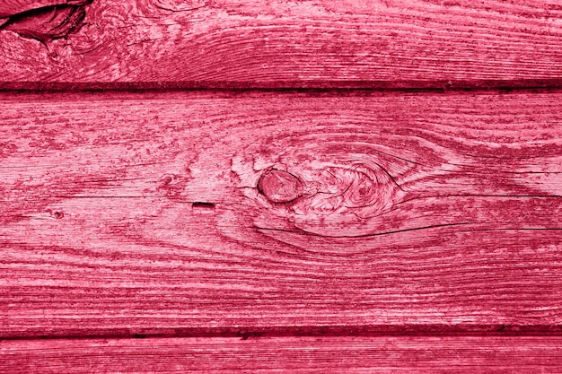 Wooden board background aged weathered red pink purple timber wood planks toned in viva magenta trend color of the year 2023