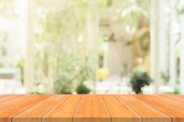 Wooden board empty table top on of blurred coffee shop background.