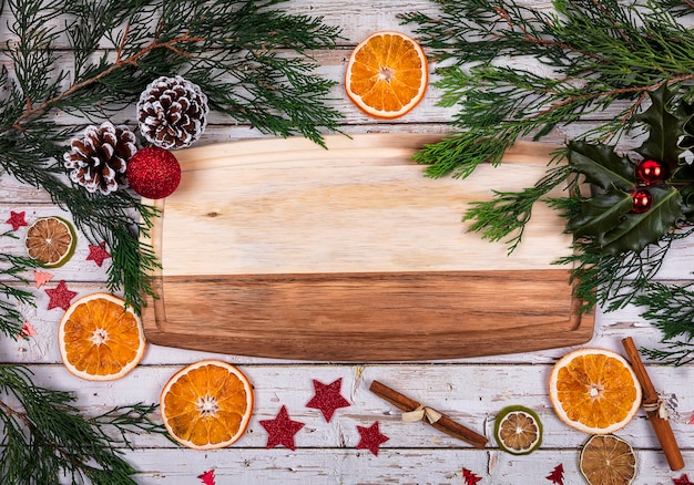 A wooden board with copy space for text in Christmas decor with Christmas tree, dry orange and cone on background