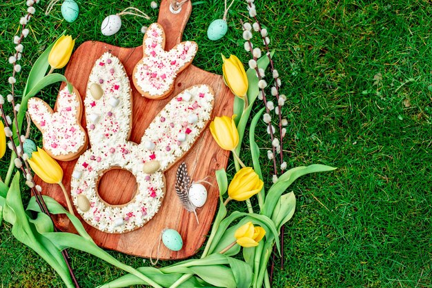 A wooden board with easter bunnies and flowers on it with easter eggs on it.