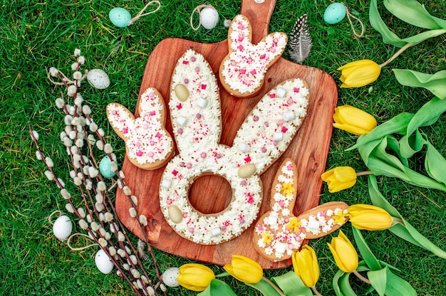 A wooden board with easter cookies on it with easter eggs on it.