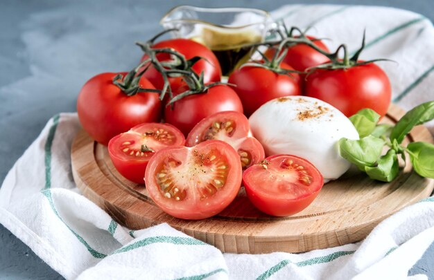 Wooden board with mozzarella tomatoes basil Italian cuisine Olive oil Close up