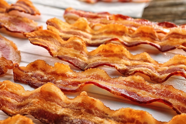 Wooden board with strips of fried bacon closeup