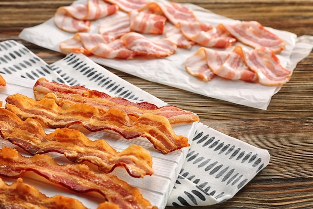 Wooden board with strips of fried bacon on table