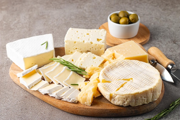 Wooden board with various cheese and olives Brie Camembert Parmesan feta blue cheese Italian