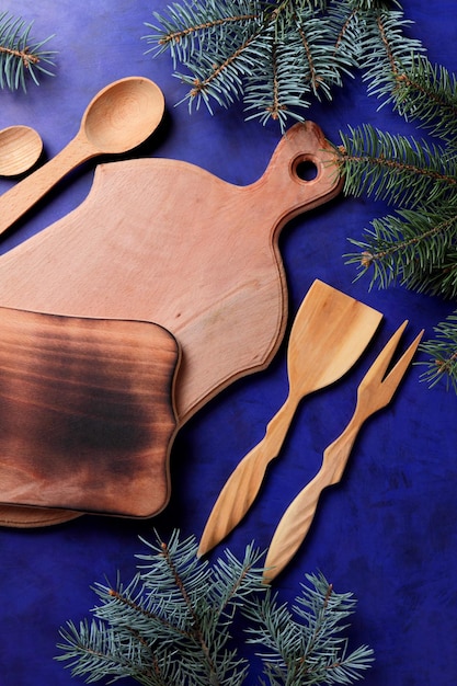 Wooden boards wooden kitchen appliances and spruce branches on a blue background View from above