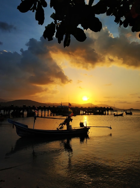 Wooden boat moored in shallow water near the beach at sunset. Romantic landscape.