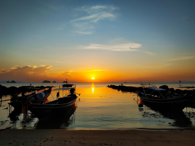 Wooden boat moored in shallow water near the beach at sunset Romantic landscape