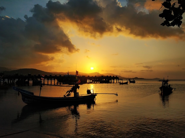 Wooden boat moored in shallow water near the beach at sunset Romantic landscape