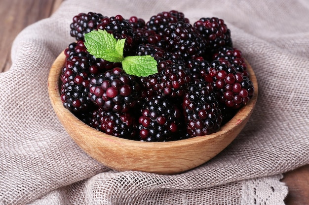 Wooden bowl of blueberries on sacking napkin on wooden background closeup