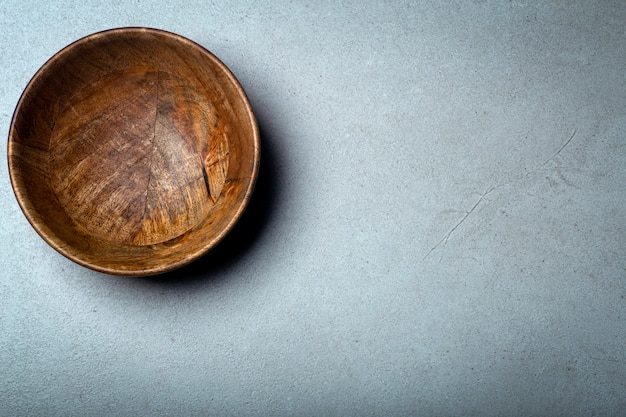 Wooden bowl on a concrete stone surface, wood and concrete.