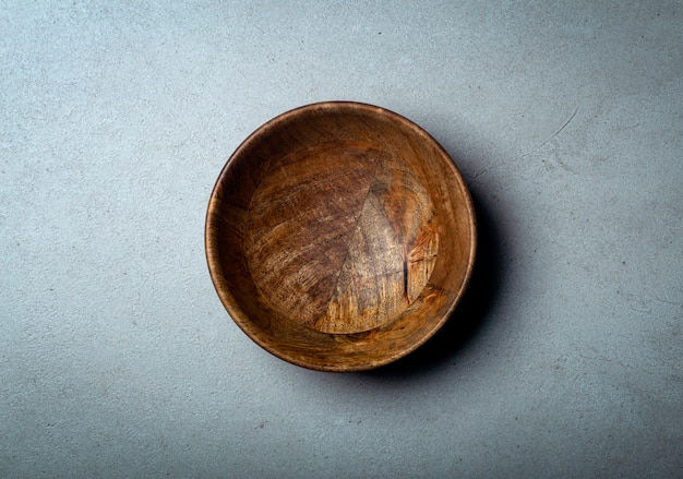 Wooden bowl on a concrete stone surface, wood and concrete.