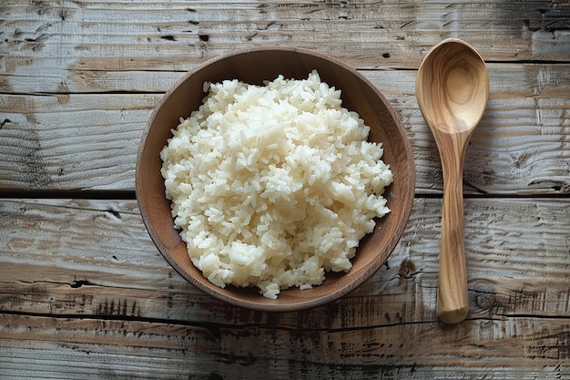 A wooden bowl filled with cooked white rice sits next to a wooden spoon on a wooden table AI