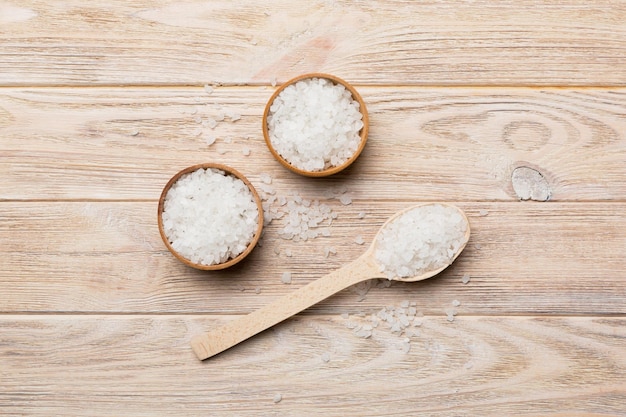 A wooden bowl of salt crystals on a wooden background Salt in rustic bowls top view with copy space