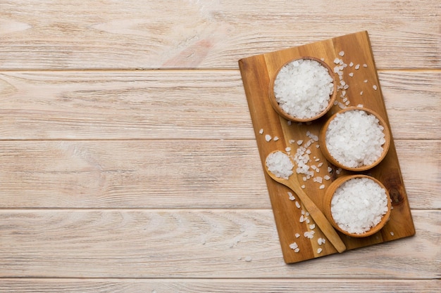 A wooden bowl of salt crystals on a wooden background Salt in rustic bowls top view with copy space