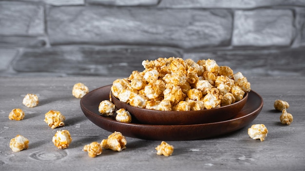 A wooden bowl of salted popcorn at the old wooden table