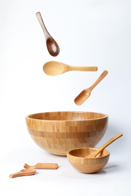 Wooden bowl spoon utensils on white background elevated flying floating