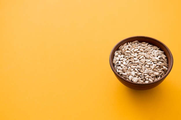 Wooden bowl of sunflower seeds on yellow