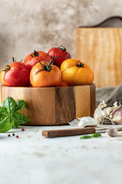 Wooden bowl of  tomatoes garlic basil pepper and knife Kitchen still life in rustic style Copy space