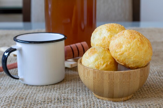 Wooden bowl with cheese bread and white coffee mug