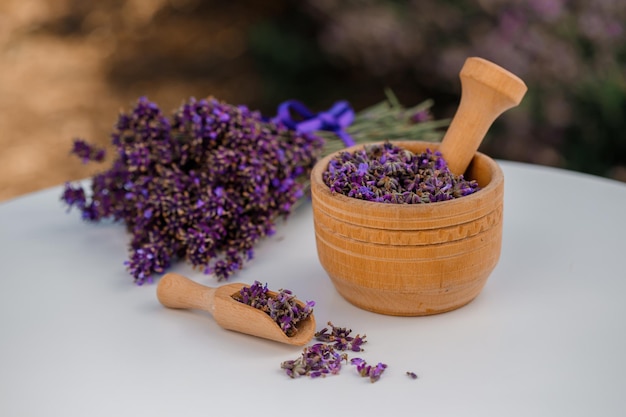 Wooden bowl with dried lavender on field background Flower herbal tea drink Aromatherapy medicine ingredient Calming beverage