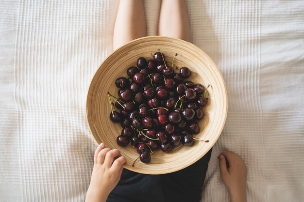 Wooden bowl with fresh juicy berries Cherries in hands Organic eco product farm Non GMO Fresh red cherries