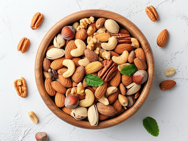 Wooden bowl with mixed nuts on white table from above Healthy food concept