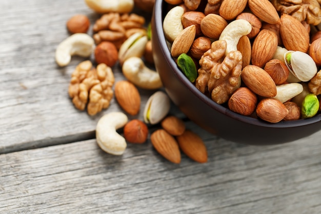 Wooden bowl with mixed nuts on a wooden gray surface