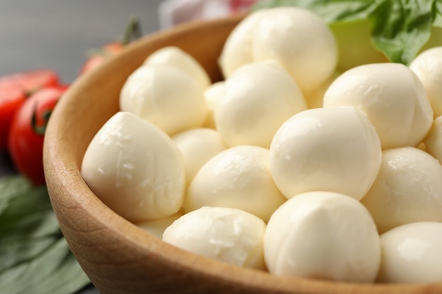 Wooden bowl with mozzarella and basil, close up