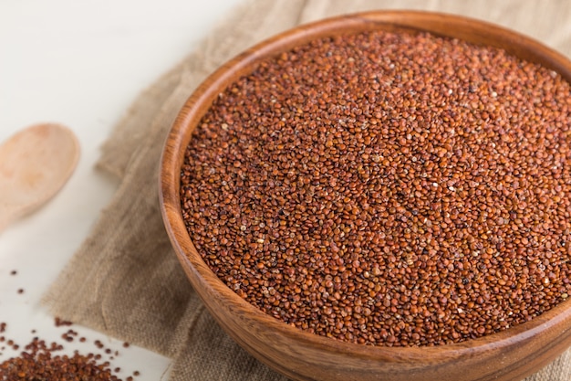 Wooden bowl with raw red quinoa seeds