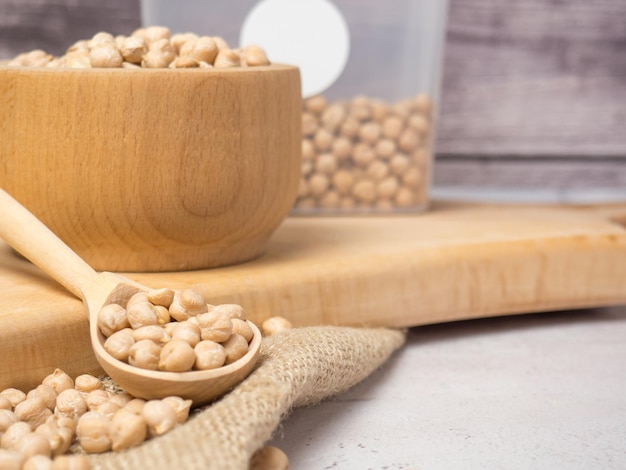 Wooden bowl and wooden spoon full of chickpeas on a light concrete background. close-up