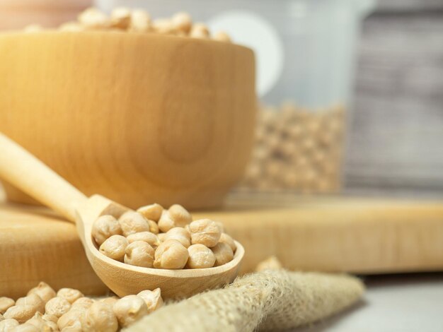 Wooden bowl and wooden spoon full of chickpeas on a light concrete background. close-up