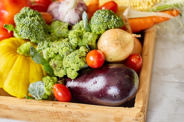 Wooden box with different fresh farm vegetables on the white background