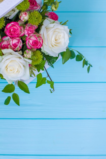 Wooden box with white and pink roses and chrysanthemums on  turquoise wooden board. Decoration of home. Flowers boxes. Wedding decoration