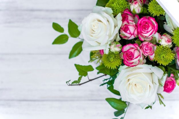 Wooden box with white and pink roses and chrysanthemums on  white wooden board. Decoration of home. Flowers boxes. Wedding decoration