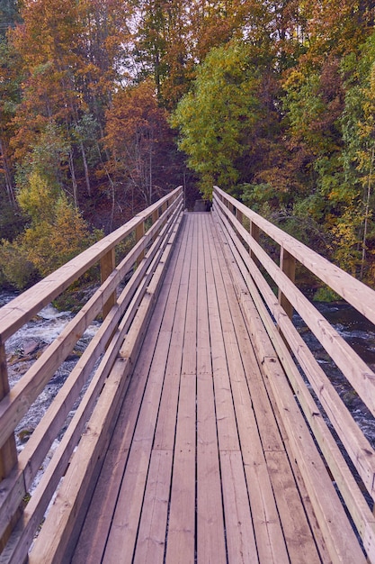 Wooden bridge over a mountain river in the autumn forest