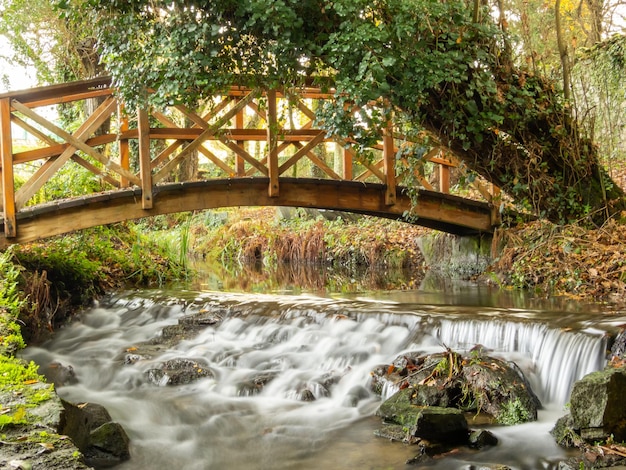 Wooden bridge over the waterfall of a silky river