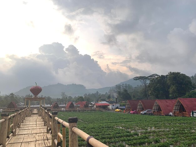 A wooden bridge with a red roof and a red roof is surrounded by a farm and mountains.