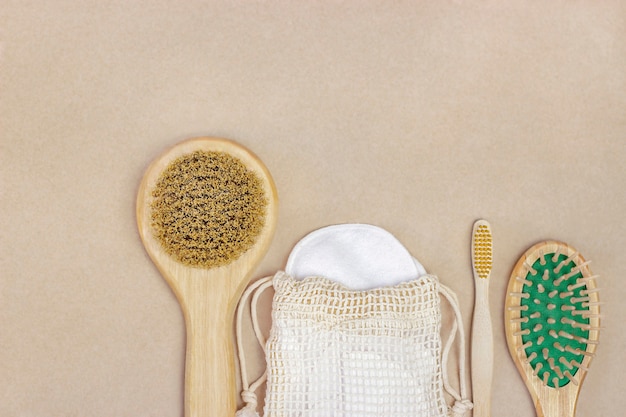 Wooden brushes comb and cotton pads lie on brown background