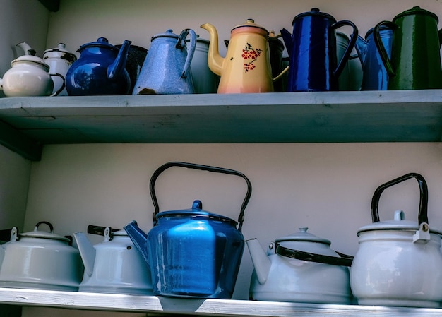 Wooden cabinet with shelves filled with blue metal teapots the concept of rustic decor of a garden plot