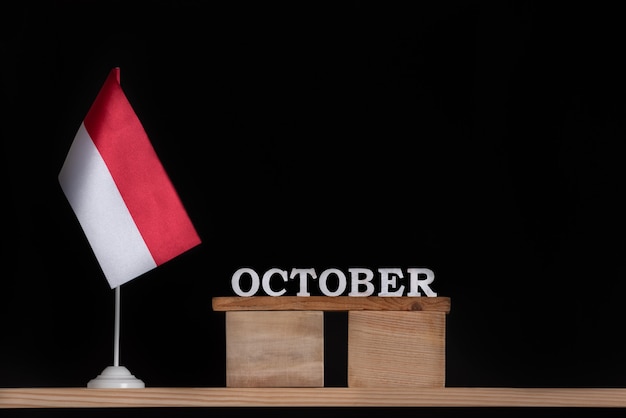 Wooden calendar of October with Polish flag on black surface. Holidays of Poland in October .