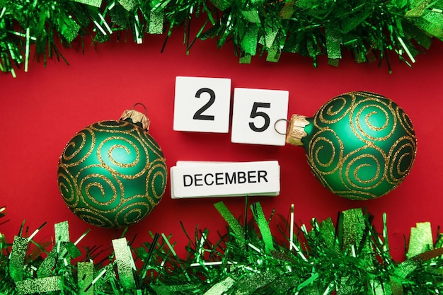 Wooden calendar with date of 25 december on red background with green christmas decoration