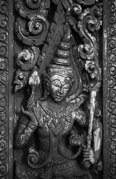 A wooden carving of a god with a stick in his hand.