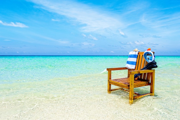 A wooden chair in the Indian Ocean with a towel shell flippers and inderwater mask