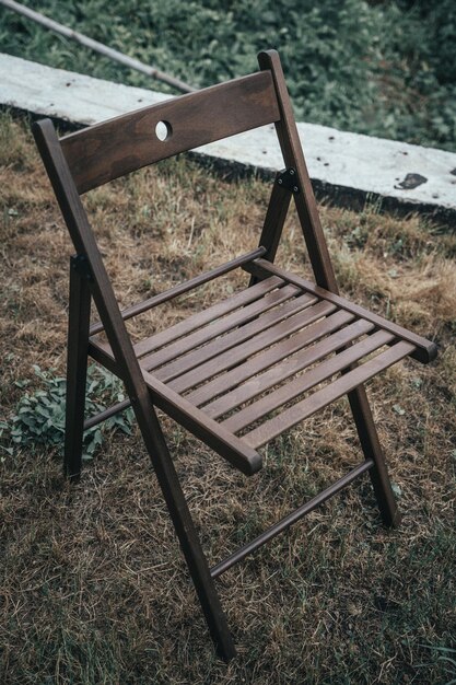 A wooden chair sits on a dry lawn Outdoor recreation