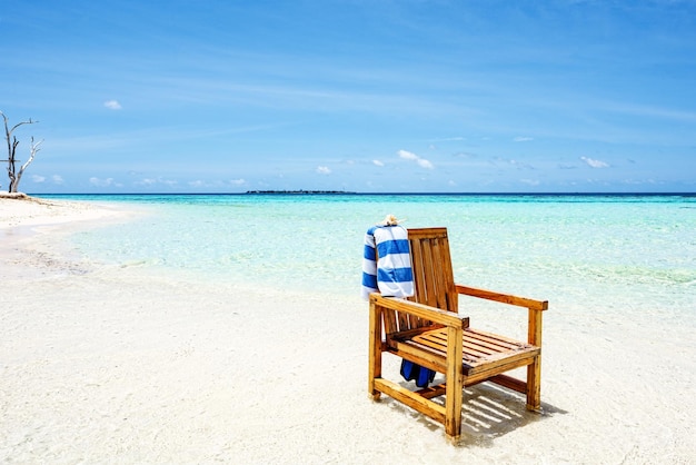 A wooden chair standing in the Indian Ocean with a towel shell and flippers