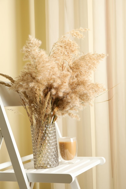 Wooden chair with vase of field flowers and glass of latte