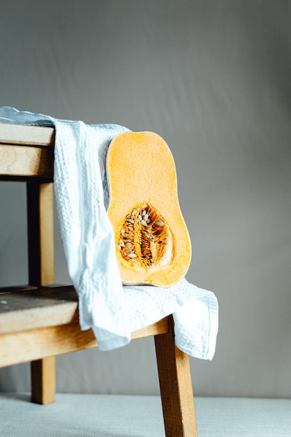 A wooden chair with a white towel on top of it with vertical half pumpkin Minimalistic backgrounds photoshoot studio